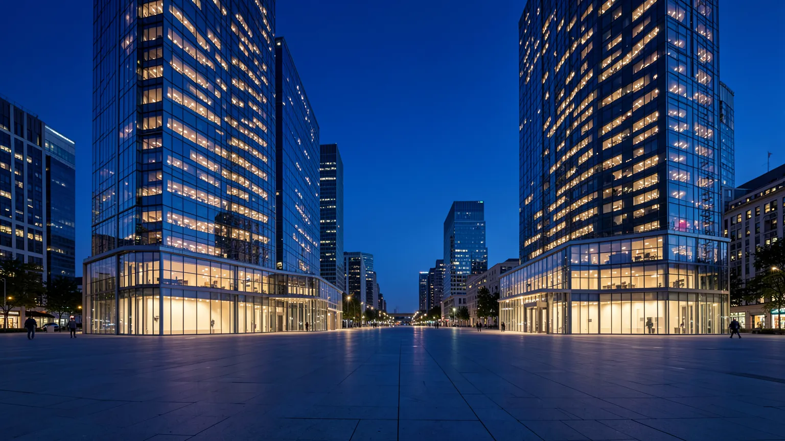 Edificios de oficinas modernos de cristal en un distrito financiero al atardecer, con luces encendidas en las plantas superiores