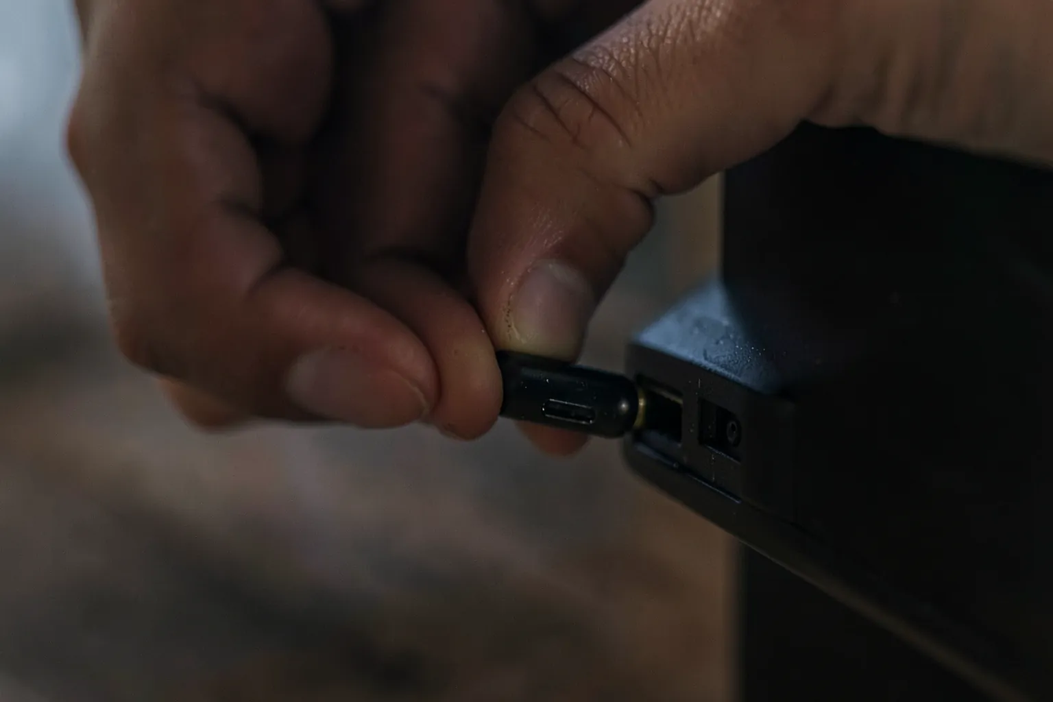 Mano conectando un pequeño dispositivo de streaming al puerto HDMI lateral de un televisor