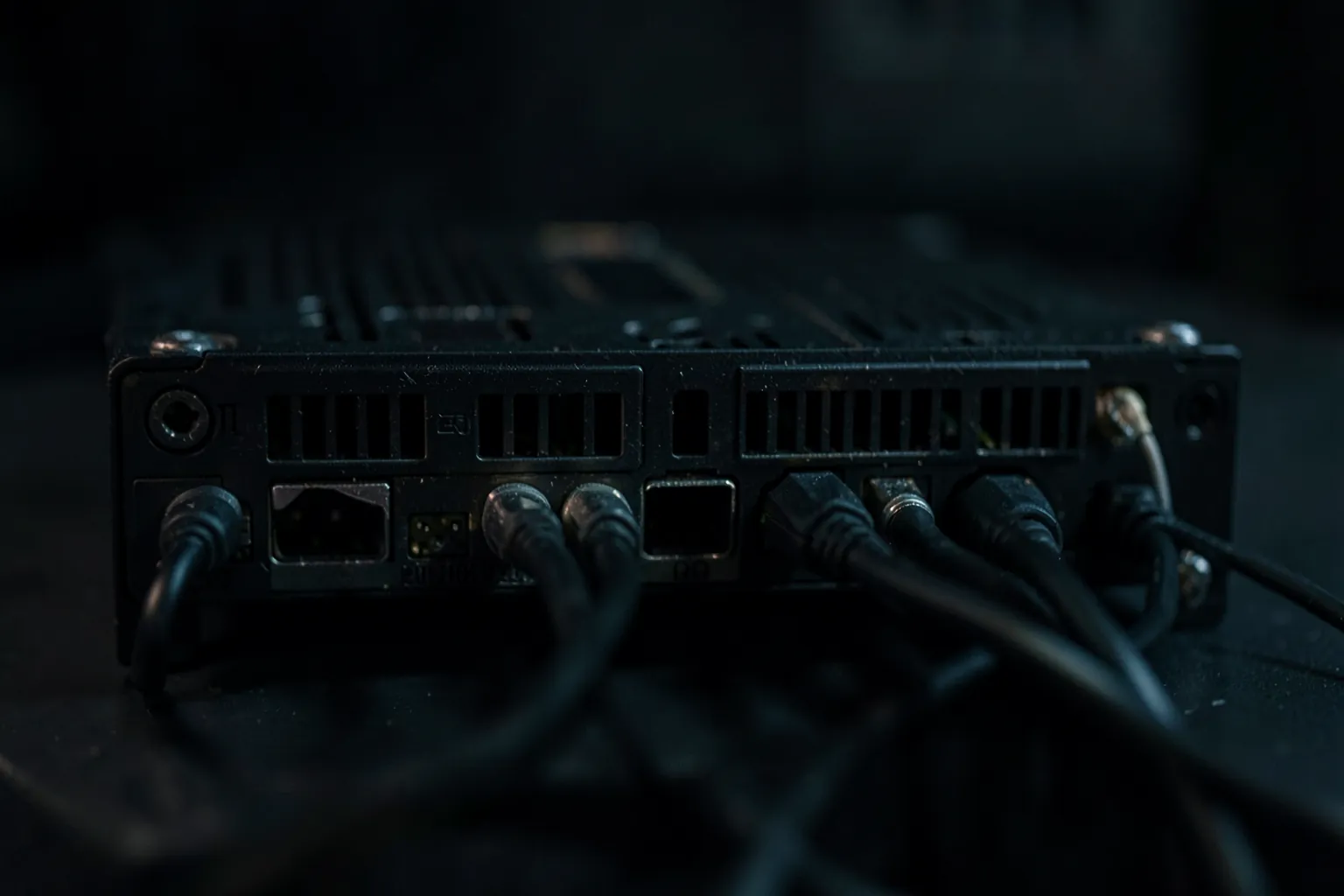 Parte trasera de una tarjeta gráfica con cables de vídeo conectados en las salidas horizontales bajo una luz tenue
