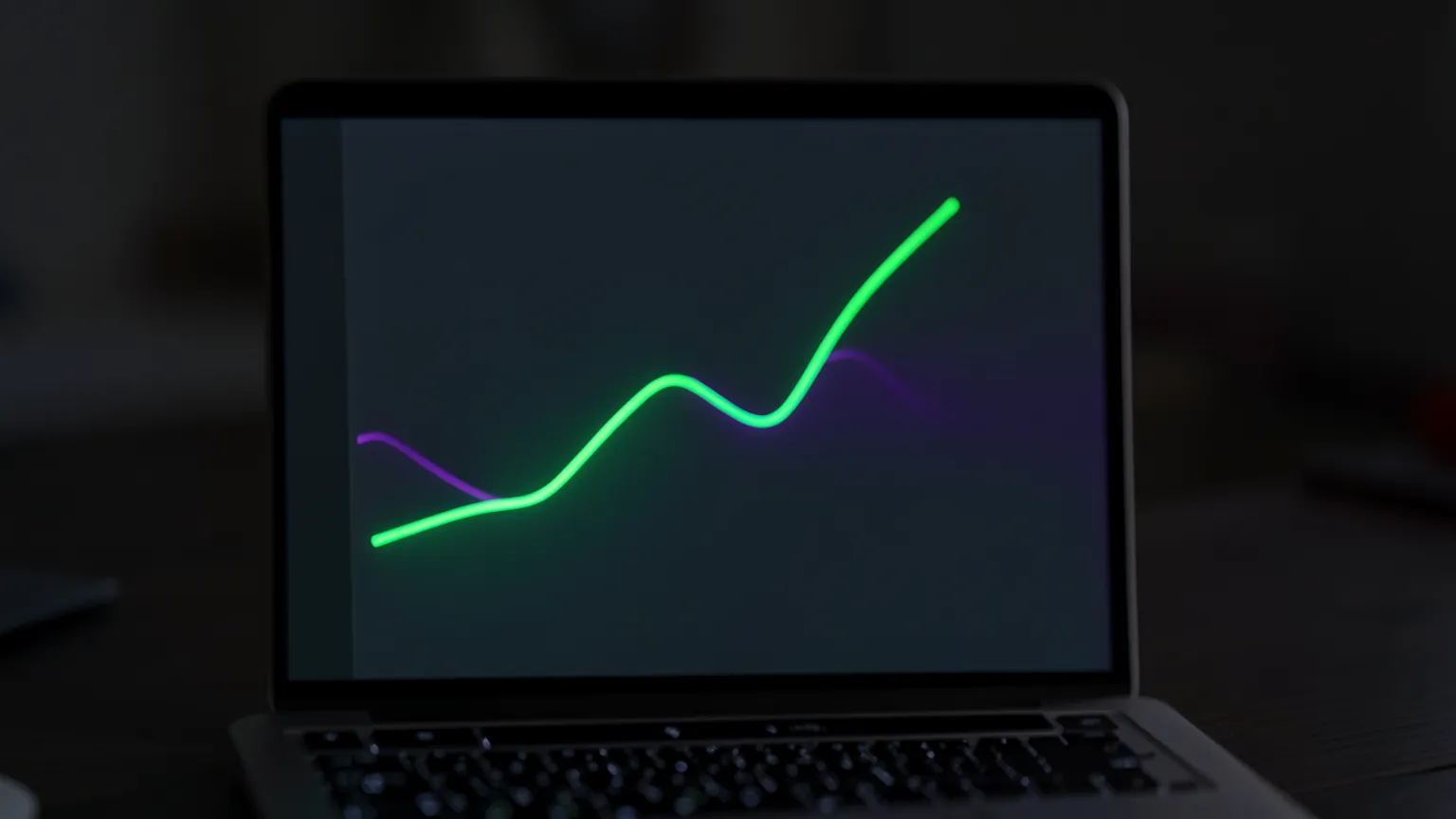 Pantalla de portátil con una gráfica de líneas que sube y baja sobre un escritorio oscuro