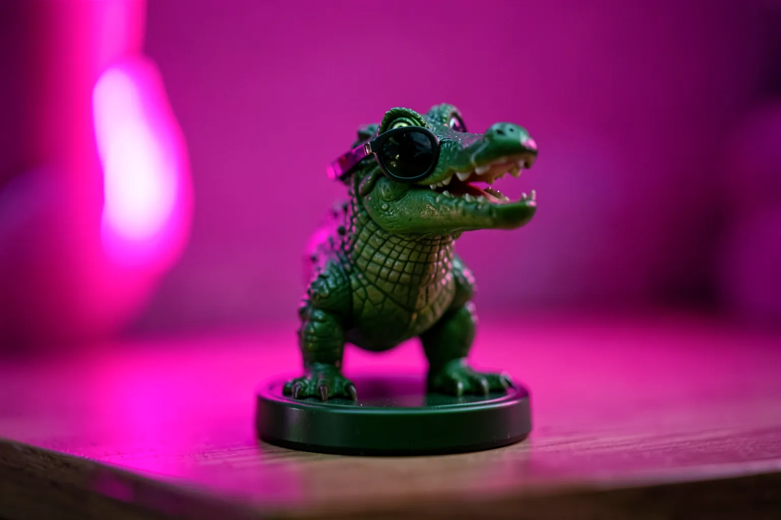 Figura de un caimán verde de plástico con gafas de sol sobre una base redonda en una estantería iluminada con neón rosa