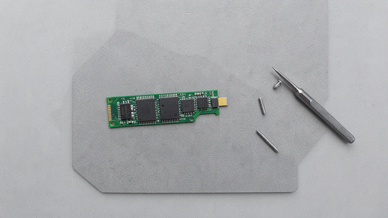 Unidad SSD NVMe M.2 junto a su tornillo sobre una alfombrilla antiestática
