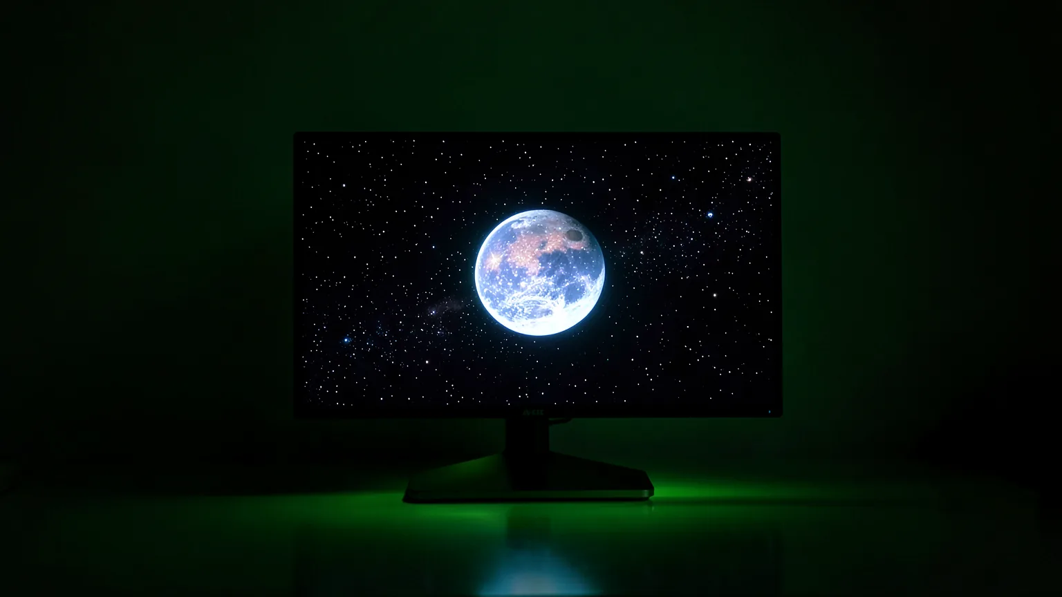 Monitor OLED en una habitación a oscuras mostrando un planeta iluminado sobre un fondo de estrellas, con reflejos de luz verde en la mesa