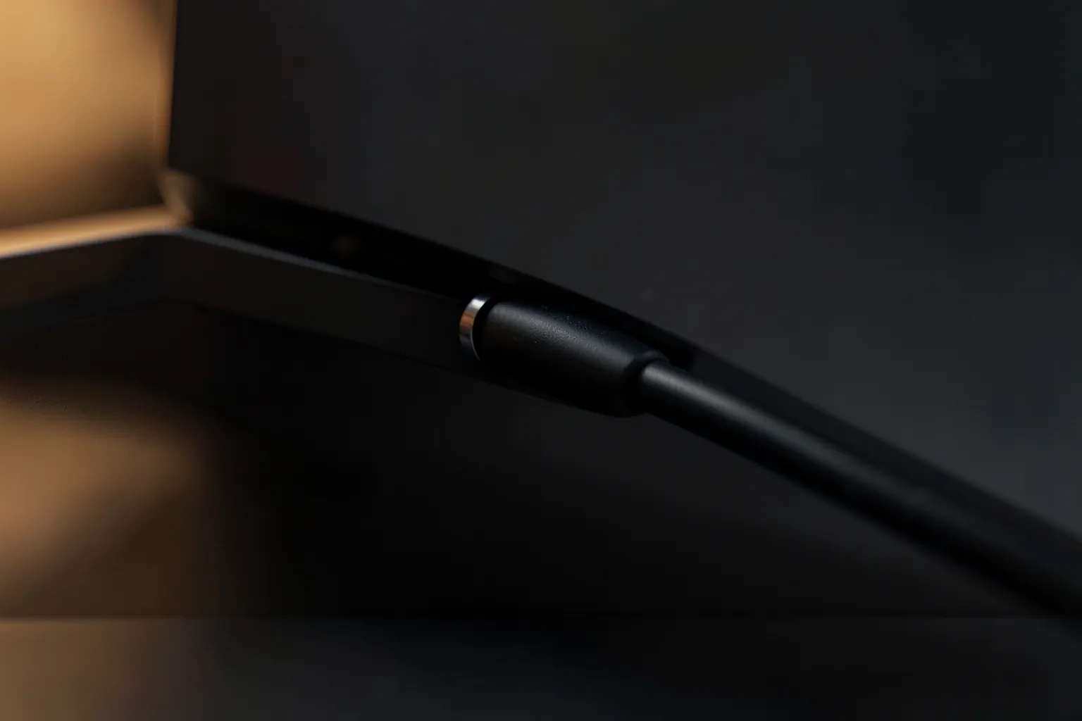 Pequeño dispositivo de streaming negro conectado al lateral de un televisor moderno, en primer plano y con luz cálida