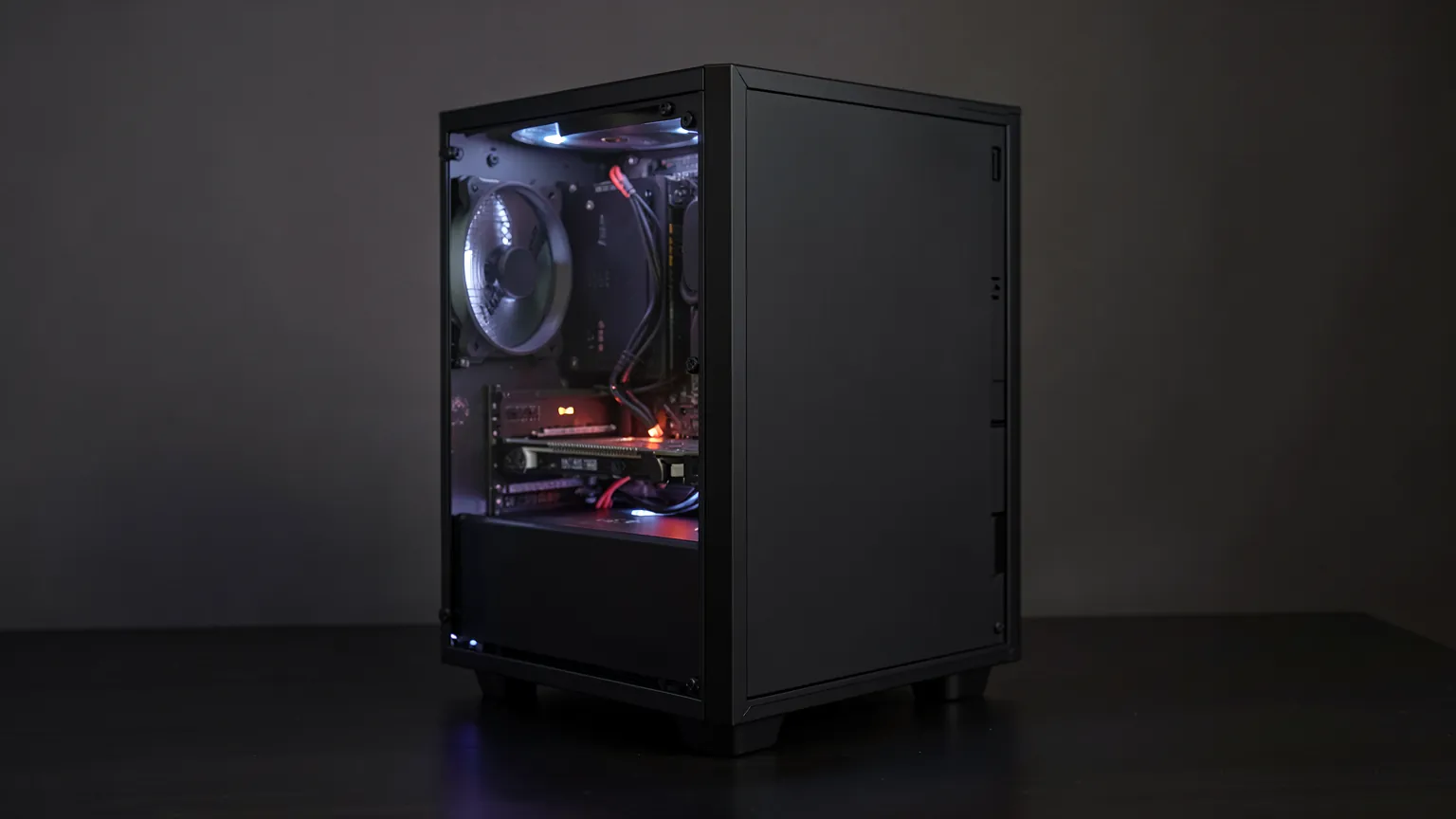 PC gaming de sobremesa con lateral de cristal y una tarjeta gráfica iluminada en su interior, sobre un escritorio oscuro