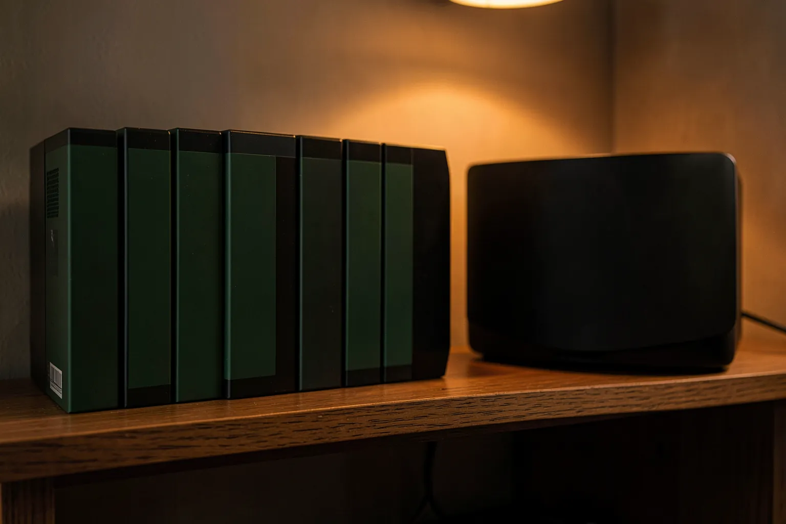 Estantería con una colección de cajas de videojuegos sin carátulas visibles junto a una consola negra
